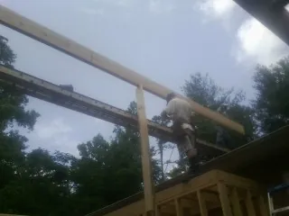 Carpenter setting a ridge beam over a new addition frame — Ice Dam Removal by Roofing Brothers in Stanhope